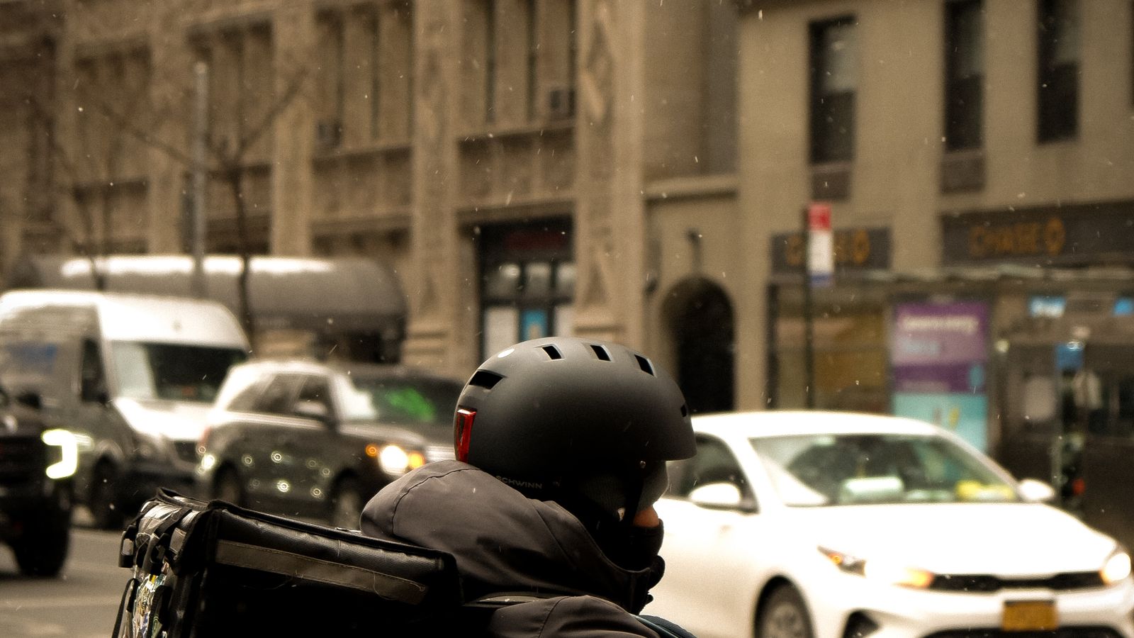 Food delivery cyclist riding through busy New York city traffic