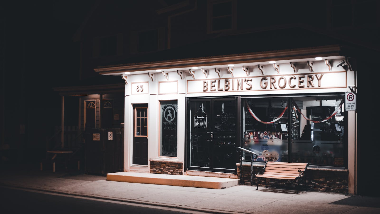 Warm storefront window of an independent neighborhood small business at night